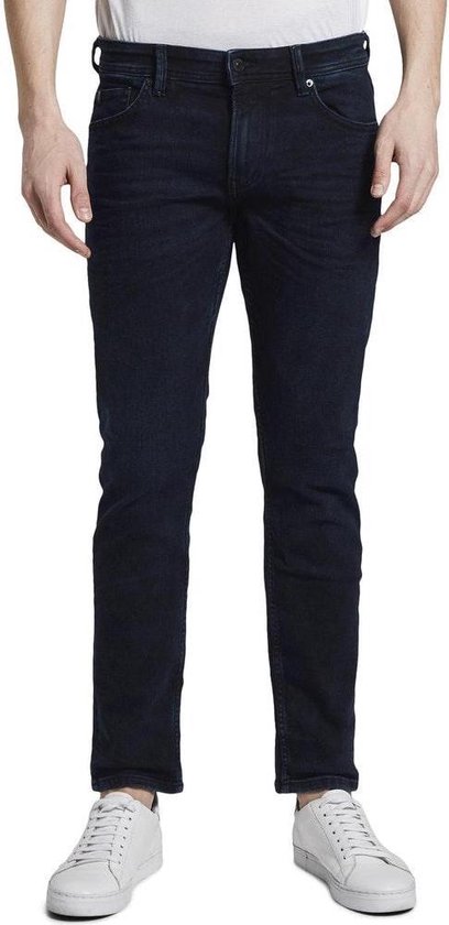 Man in een donkerblauwe jeans en een wit shirt.