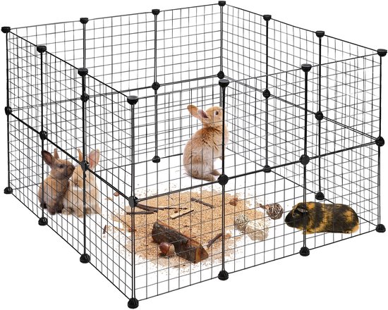 Een vierkante, zwarte metalen ren met openingen, met daarin drie konijntjes, een cavia, takken, speeltjes en zand.