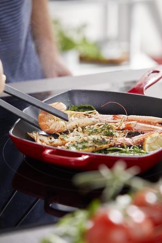 Langoustines en zalm worden gegrild in een rode grillpan.