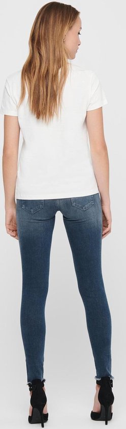 Achterkant van een model in een blauwe skinny jeans met rafels aan de zoom.