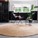 Een rond, natuurlijk jute vloerkleed in een woonkamer met een vlinderstoel en grote plant.