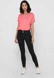 Coralroze t-shirt met omgerolde mouwen en een ronde hals, gedragen door een model met een spijkerbroek.