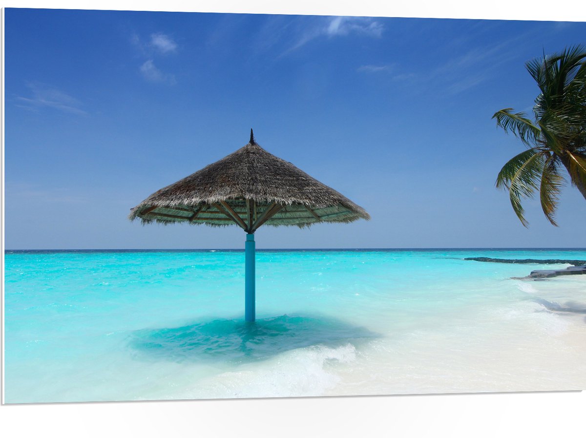 PVC Schuimplaat - Rieten Parasol op het Strand bij het Blauwe Water - 105x70 cm Foto op PV