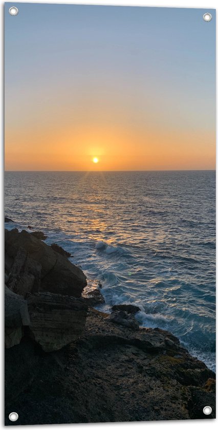 Tuinposter – Golven tegen de Rotsen aan bij Zonsondergang - 50x100 cm Foto op Tuinposter (wanddecoratie voor buiten en binnen)