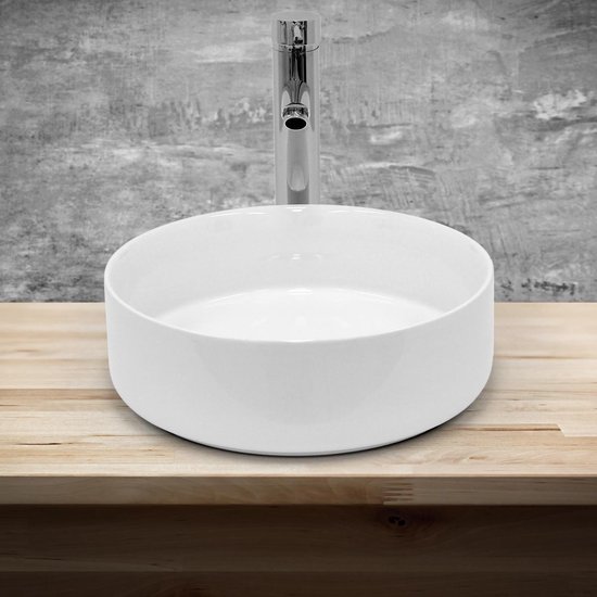 Ronde witte wastafel op een houten plank met een glanzende chromen kraan.