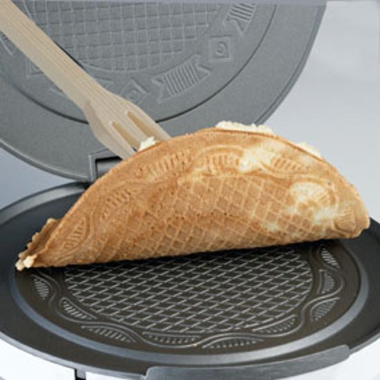 Wafelijzer met een halfgevormde, goudbruine wafel en een tang.