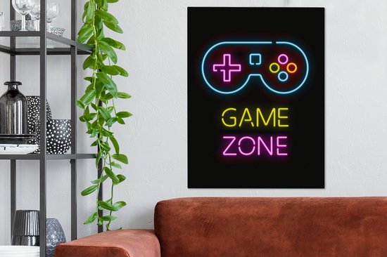 Panneau néon avec un joystick et le texte 'GAME ZONE' en bleu, jaune et rose, suspendu au-dessus d'un canapé marron.