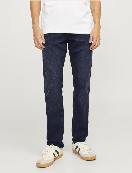 Blauwe jeans gedragen door een man met een wit T-shirt en witte sneakers.