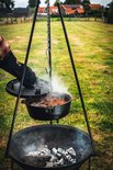 Gietijzeren Dutch oven met deksel, hangend boven gloeiende kolen in een vuurkorf.