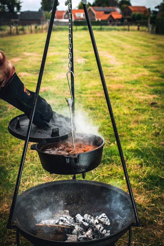 Gietijzeren Dutch oven met deksel, hangend boven gloeiende kolen in een vuurkorf.