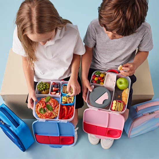 Kinderen openen lunchboxen; linkse blauw-roze, rechtse roze met eten. Links een blauwe, rechts een pastelkleurige lunchtas.