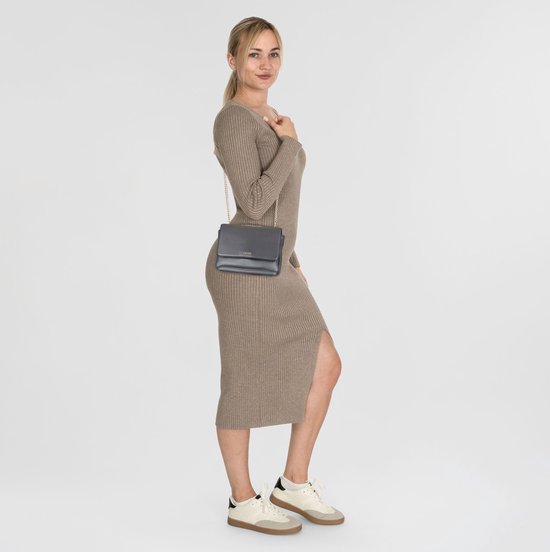 Une femme porte un sac bandoulière Liu Jo anthracite avec une robe.