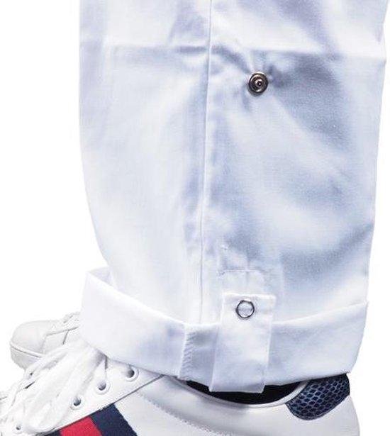 Onderkant van witte werkbroek met opgerolde pijpen, drukknoopjes en witte sneakers.