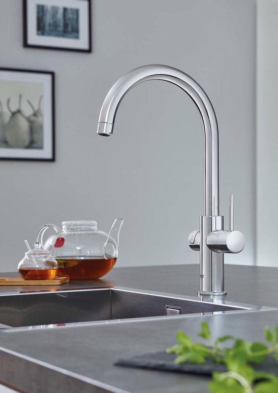 Chroom GROHE keukenkraan met gebogen uitloop, naast een glazen theepot met thee en een theeglas.