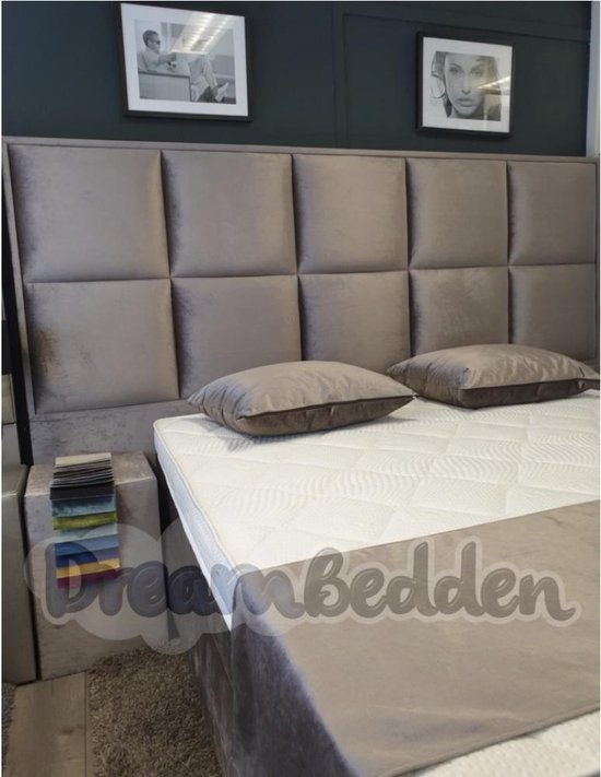Bed met een taupe gestoffeerd hoofdbord met vierkante patronen, twee kussens en stofstalen.