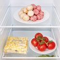 Binnenzijde koelkast met een plateau met roze en witte gebakjes en een zakje aardappeltjes.