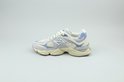 Lichtgrijze New Balance 9060 sneaker met beige suède en lichtblauwe mesh-accenten, staande op een witte achtergrond.