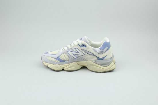 Lichtgrijze New Balance 9060 sneaker met beige suède en lichtblauwe mesh-accenten, staande op een witte achtergrond.