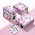 Drie roze geschenkdozen van Arrtx met een vrouw en wolken. Een rij van zeven gekleurde Arrtx acrylmarkers ligt voor de dozen.