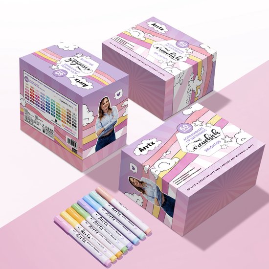 Drie roze geschenkdozen van Arrtx met een vrouw en wolken. Een rij van zeven gekleurde Arrtx acrylmarkers ligt voor de dozen.