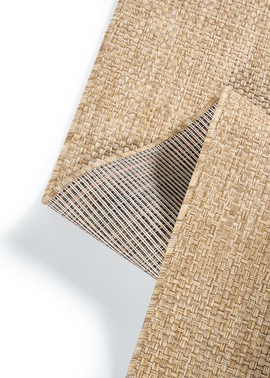 Un tapis beige chiné est soulevé sur le coin, révélant le dessous rayé avec des accents rouges.