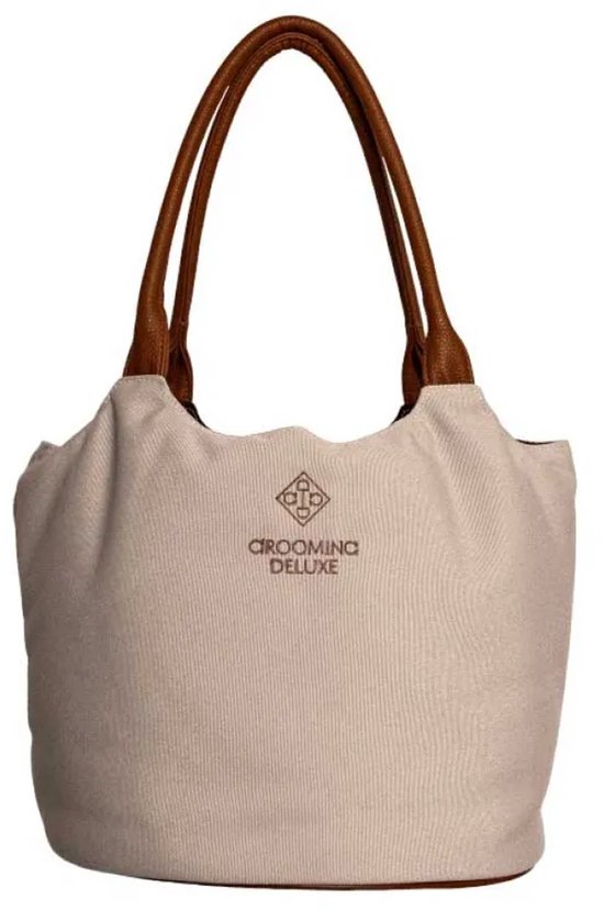 Beige canvas tas met bruine leren hengsels en bruine bodem. "GROOMING DELUXE" logo midden op de voorkant.