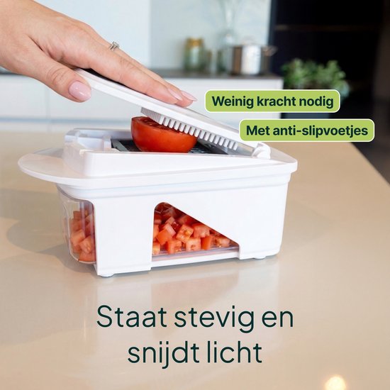 Witte groentesnijder met een tomaat die wordt gesneden, met rode blokjes groenten in de opvangbak. Tekst 'Staat stevig en snijdt licht'.