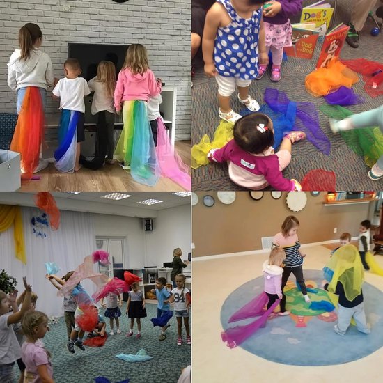 Kinderen dragen gekleurde danssjaals als een regenboog, en spelen ermee.
