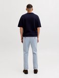 Man van achteren gezien met donkerblauw poloshirt en lichtblauwe pantalon met ruitpatroon en omgeslagen pijpen.