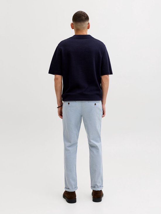 Man van achteren gezien met donkerblauw poloshirt en lichtblauwe pantalon met ruitpatroon en omgeslagen pijpen.
