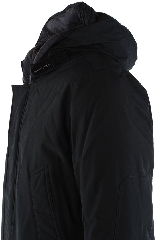 Close-up van de capuchon van een zwarte Woolrich jas met het Woolrich-logo op een band.