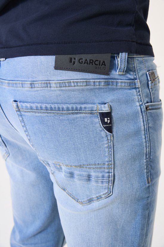 Detail van de achterkant van een lichtblauwe spijkerbroek met een zwart Garcia-label.