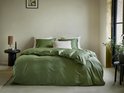 Opgemaakt bed met olijfgroene dekbedovertrekken, kussenslopen en een off-white sierkussen.