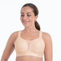 Frontaal aanzicht van een lachend model in een beige sportbeha met mesh-detail op de cups en brede bandjes.