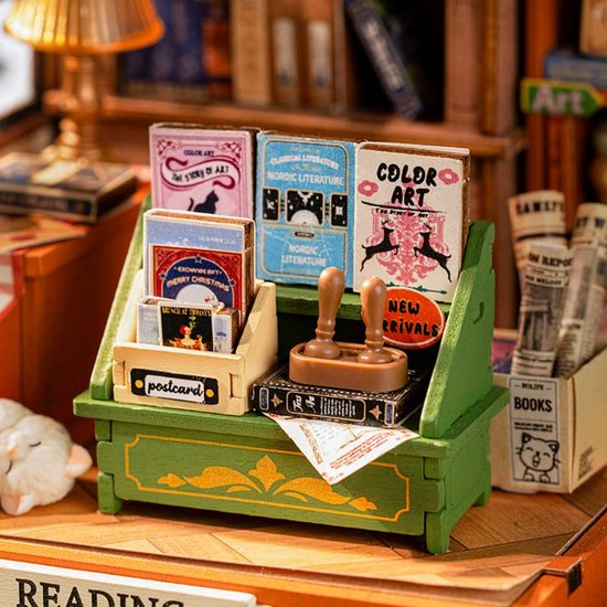 Close-up van de miniatuur boekenwinkel balie met boeken, ansichtkaarten, een stempel en kranten.
