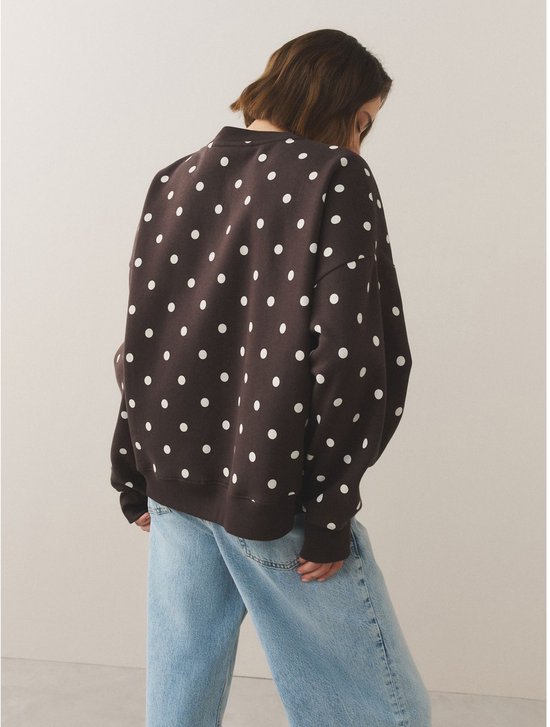 Donkerbruine sweater met witte polkadotprint, gedragen door een model op de rug gezien.