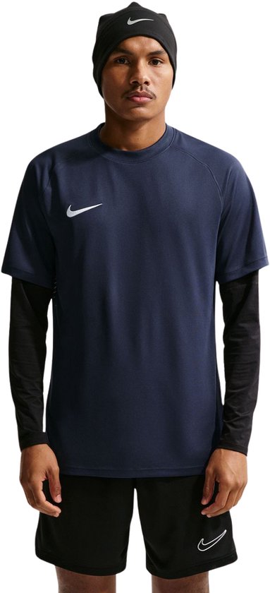Man met donkerblauwe Nike Dri-FIT Park VIII T-shirt met witte swoosh. Draagt ook een zwarte muts en een zwarte longsleeve.