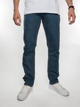 Man in een wit T-shirt en spijkerbroek met een middenblauwe wassing, gedragen met witte sneakers.