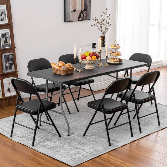 Eettafel met zes zwarte inklapbare stoelen, gedekt met eten, kaarsen en gebak, in een sfeervolle eetkamer.