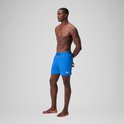 Homme les mains derrière le dos, portant un short de bain bleu Speedo avec logo blanc.