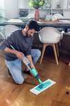 Man met Leifheit Easy Spray XL vloerwisser in een moderne woonkamer.