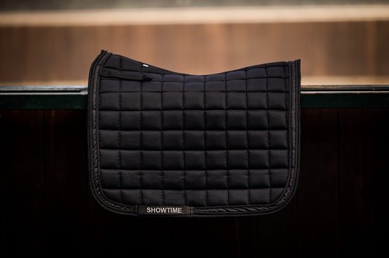 Zwart dressuur zadeldek met 'SHOWTIME' logo, op een donkere achtergrond.