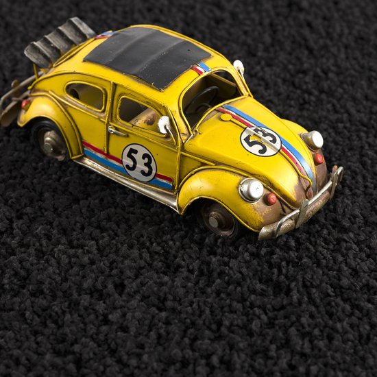 Voiture jouet jaune en métal avec le numéro 53, sur un tapis shaggy noir.