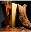 Gouden parfumflesje tussen stukken ruw hout.