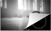 KitchenYeah® Inductie beschermer 81.2x52 cm - Verschillende kettlebellgewichten op de vloer in een fitnessruimte - zwart wit - Kookplaataccessoires - Afdekplaat voor kookplaat - Inductiebeschermer - Inductiemat - Inductieplaat mat