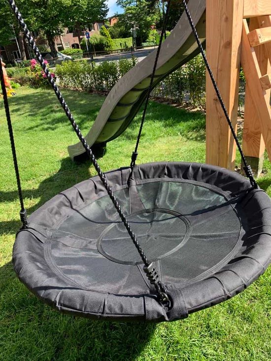 Zwarte nestschommel met ronde zitting, opgehangen aan een schommelset in een tuin.