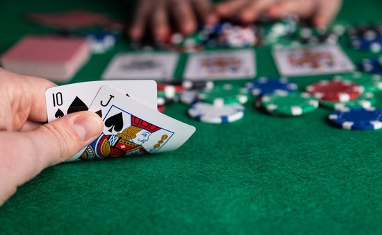 Speler houdt 10 schoppen en Boer schoppen vast, met pokeren fiches en kaarten op groen kleed.