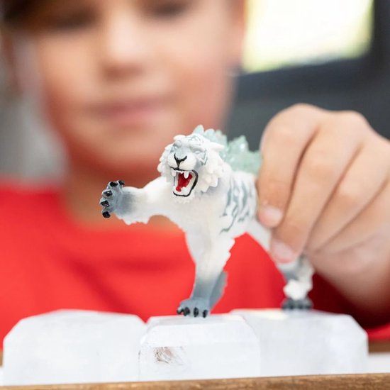 Kind houdt witte tijgerfiguur met grijze strepen en ijskristallen vast, deels zichtbaar.
