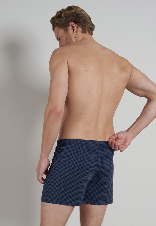 Man, van achteren gezien, met donkerblauwe boxershorts met pied-de-poule patroon.