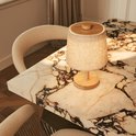 Tafellamp met linnen kap, houten voet en bovenzijde, geplaatst op een marmeren tafel.
